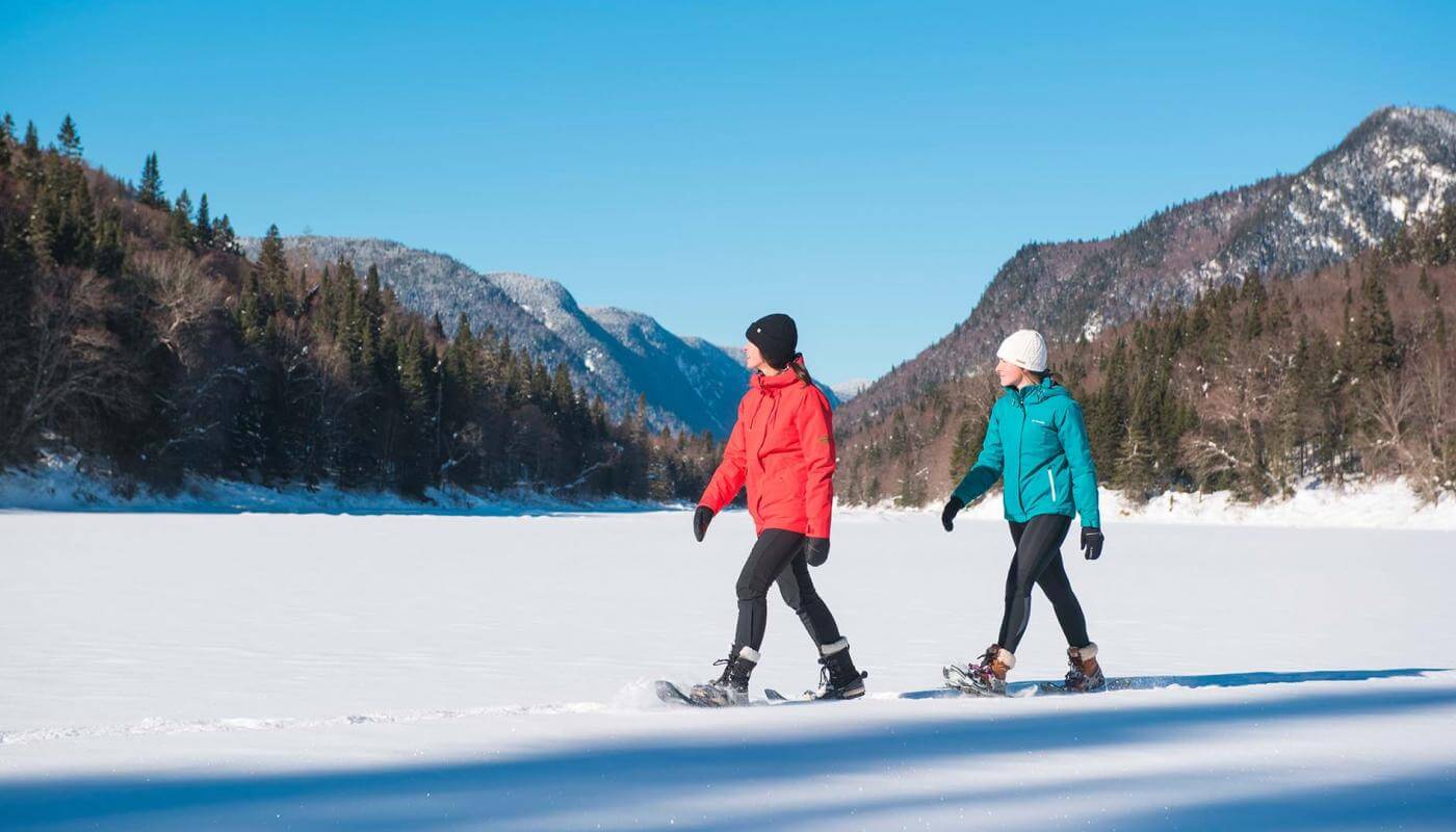 Two girls on snowshoes enjoy a sunny winter day in Jacques-Cartier National Park.