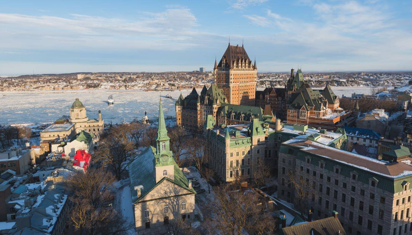 Vue aérienne du Vieux-Québec en hiver, avec le fleuve Saint-Laurent glacé, le Château Frontenac et l'église Holy Trinity. 