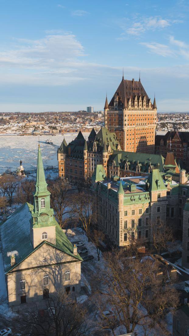 Vue aérienne du Vieux-Québec en hiver, avec le fleuve Saint-Laurent glacé, le Château Frontenac et l'église Holy Trinity. 
