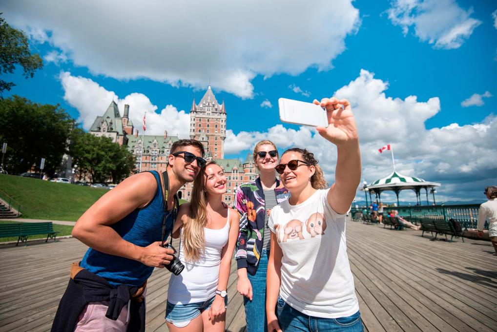 Quatre jeunes adultes se prennent en photo sur la terrasse Dufferin, à proximité du Château Frontenac.