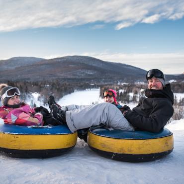 Une famille s'apprête à glisser sur des chambres à air au Village Vacances Valcartier, en hiver.