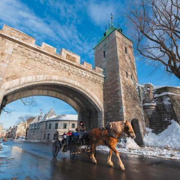  Two tourists in horse-drawn carriages pass under the Saint-Louis Gate in winter.