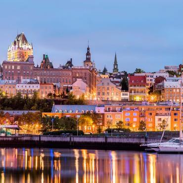 Sailboats at Bassin Louise, in the Old Port of Québec, with a view of the illuminated Old Québec.
